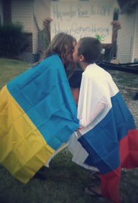 #44 Two people kissing across the Russia/Ukraine Boarder. If safety is a concern the image may be two people anywhere wrapped in a Russian and Ukrainian flag kissing each other. 